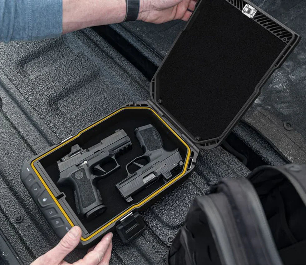 Open biometric safe in vehicle trunk holding two handguns, showing secure storage