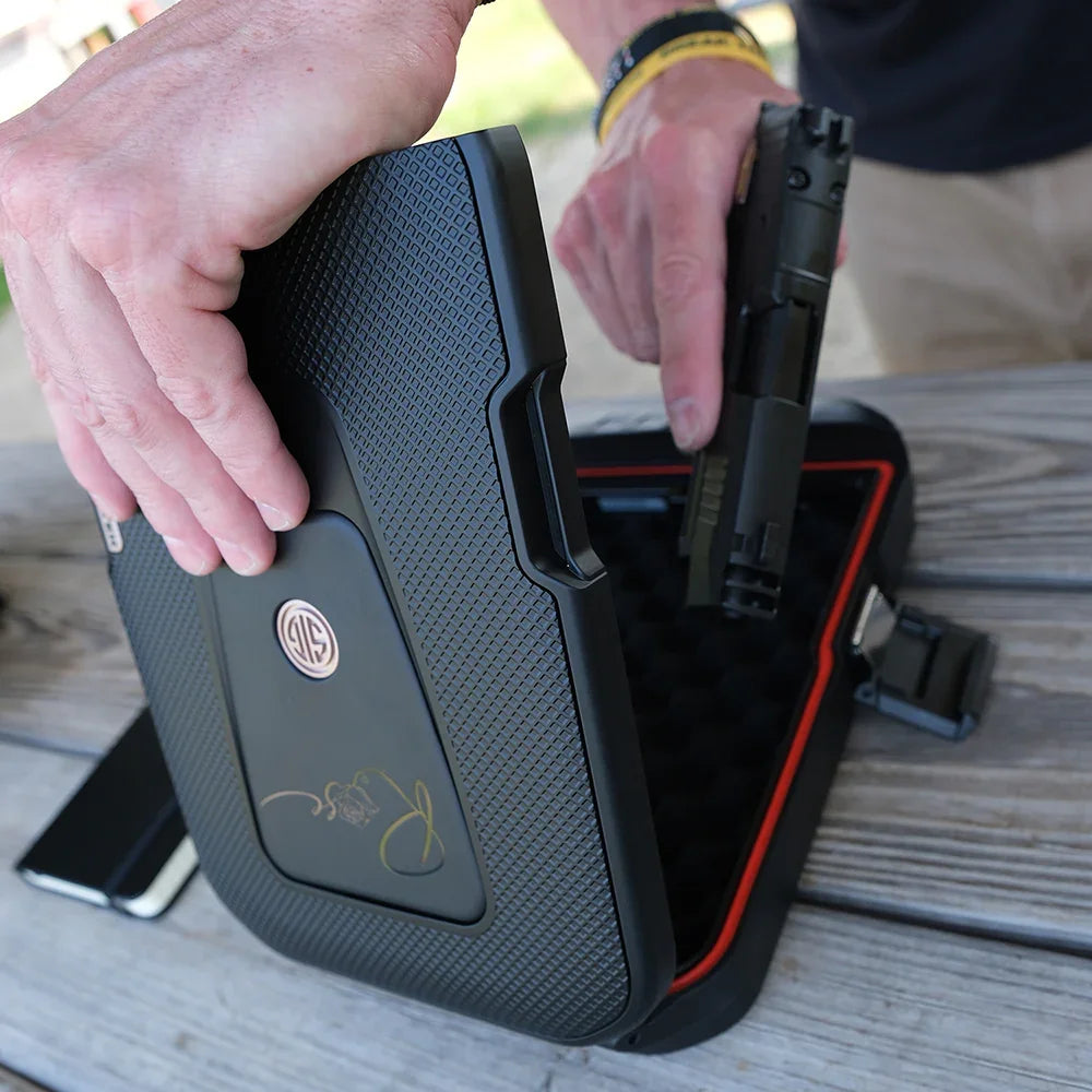 Secure portable gun safe with textured black finish, being opened outdoors on a wooden table