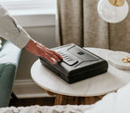Person securing a biometric safe with keypad on a bedroom nightstand