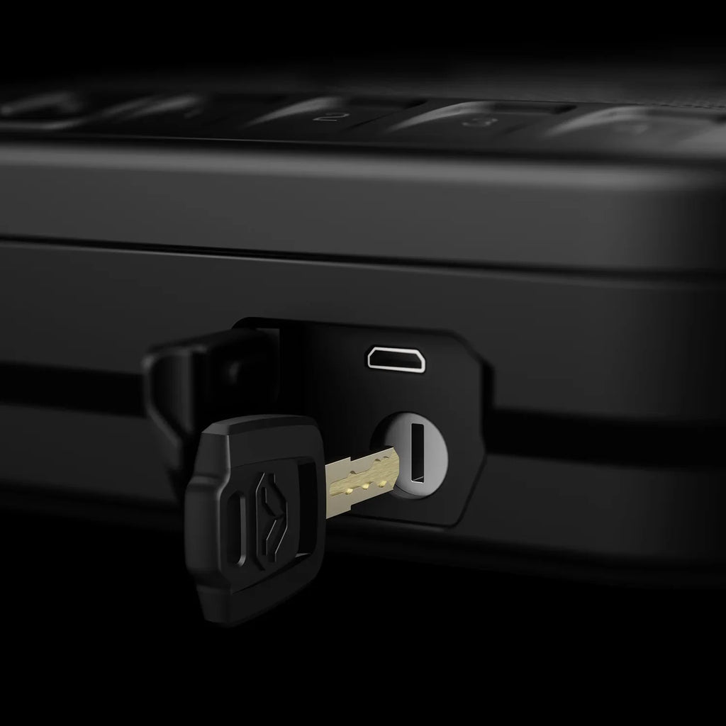 Close-up of a black portable safe with a key inserted in the lock and USB port visible.