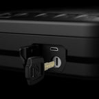 Close-up of a black portable safe with a key inserted in the lock and USB port visible.