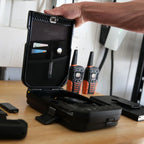 Open biometric safe on table storing cards and documents, with walkie talkies nearby