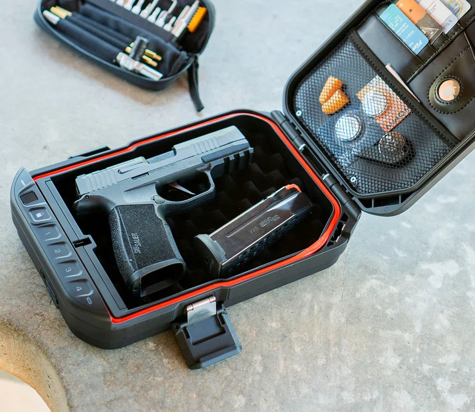 Biometric safe open displaying a handgun, magazine, cards, and accessories on concrete surface.