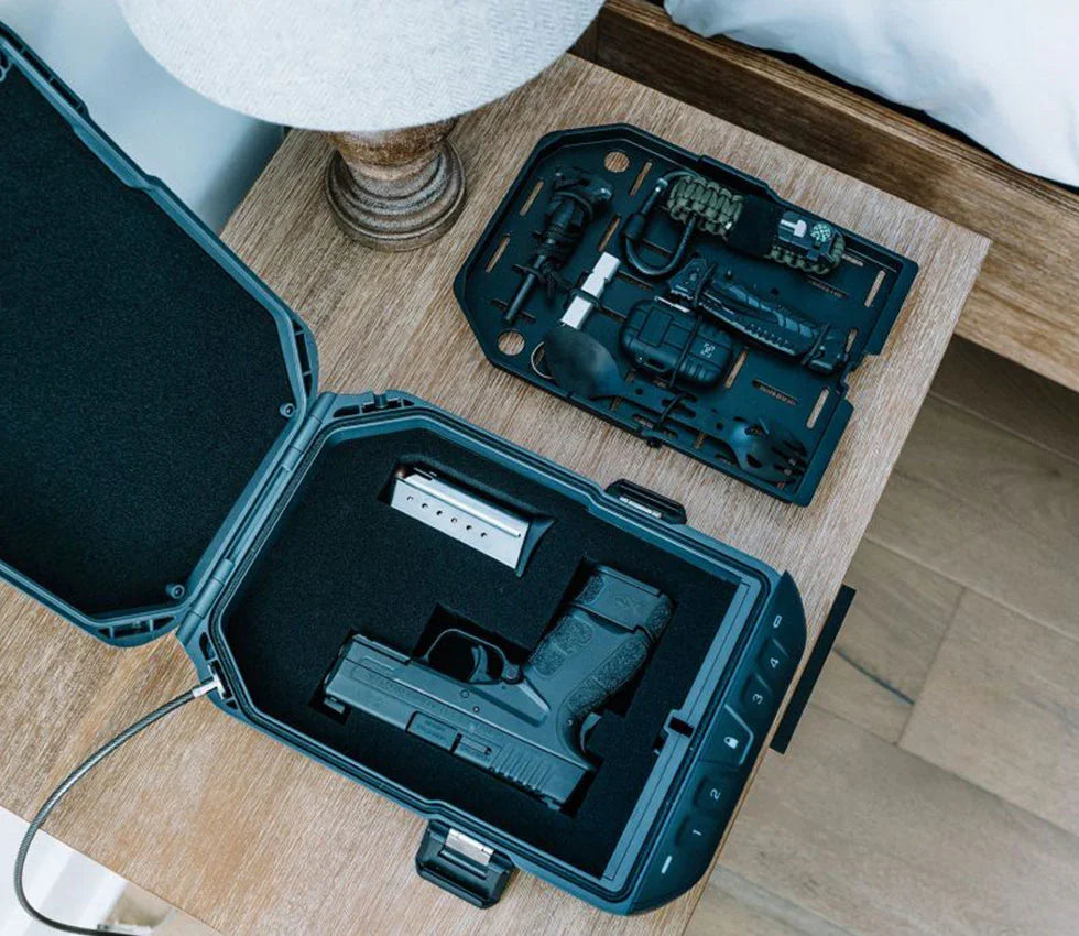 Open biometric safe with handgun and magazine on nightstand, tactical gear tray nearby