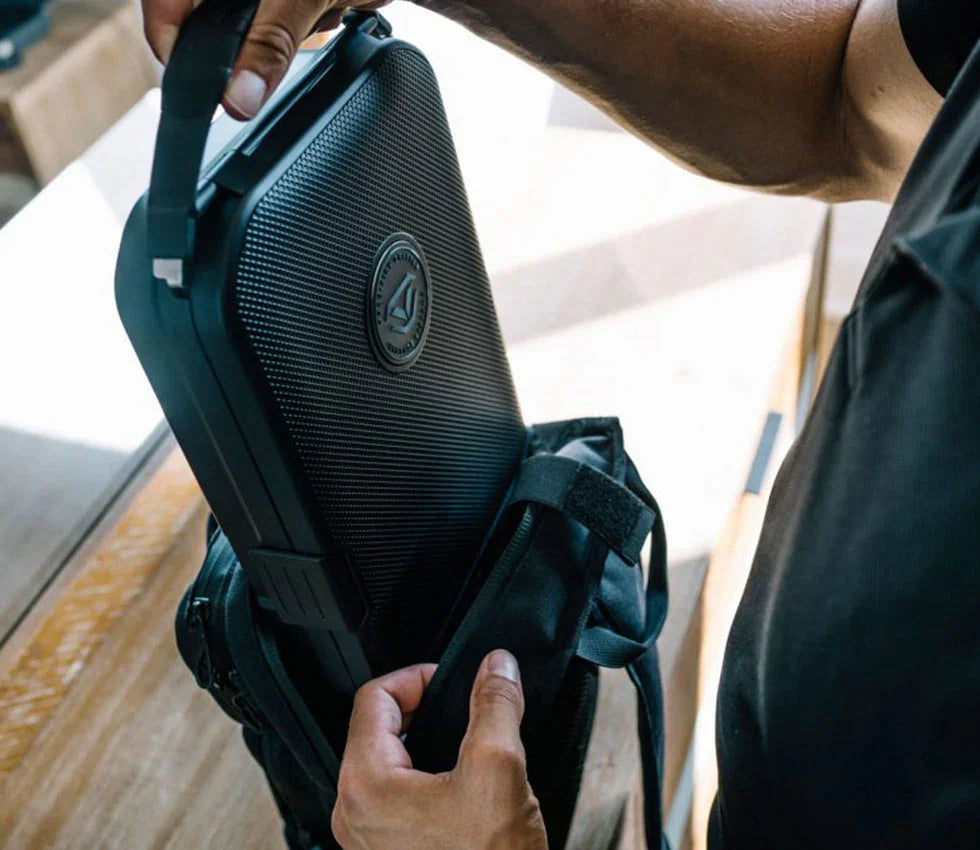 Man placing compact travel safe with textured black surface into a backpack