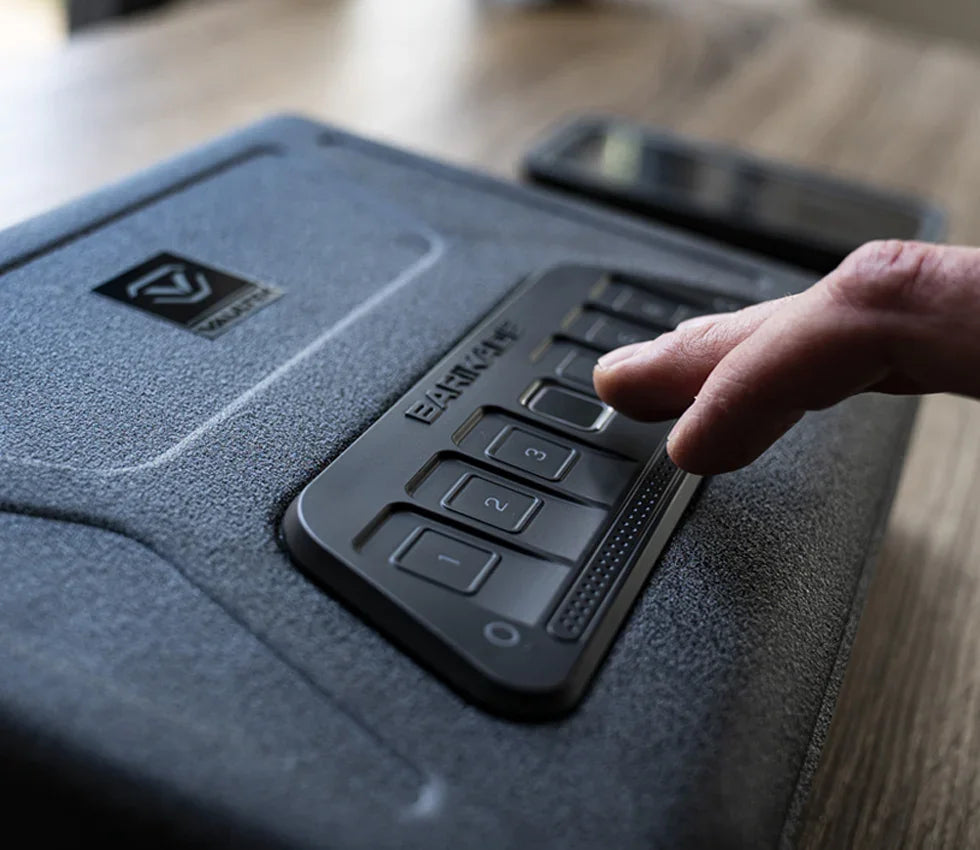 Hand entering code on textured keypad of electronic safe on wooden surface