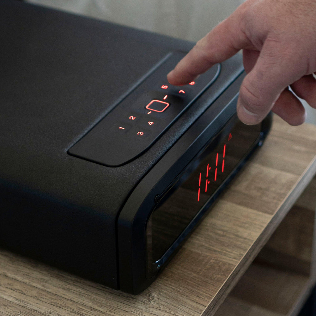 Person using biometric keypad on sleek black home safe with digital display