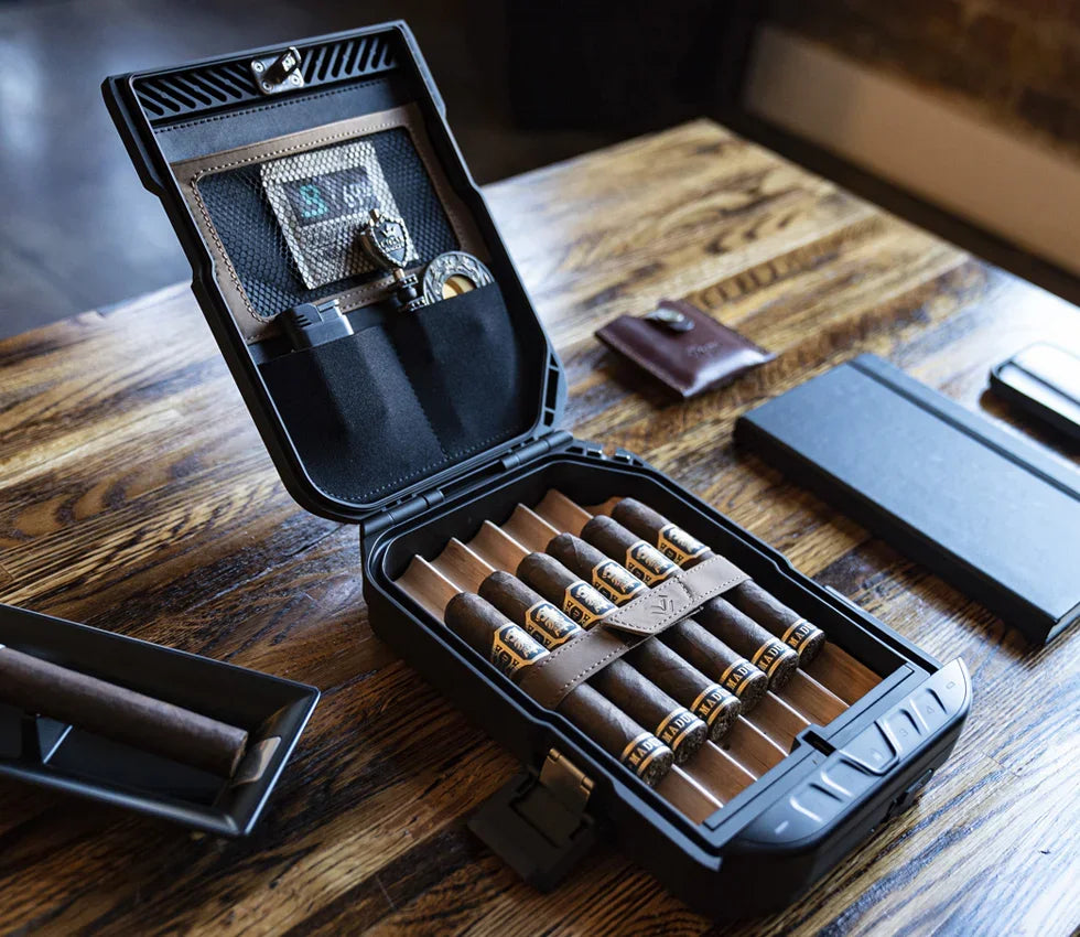 Portable cigar humidor safe open on a wooden table, holding cigars and accessories.