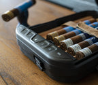 Closeup of a portable safe with a keypad, storing cigars on a wooden surface.