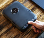 Person entering code on compact biometric safe with textured black exterior on wooden table