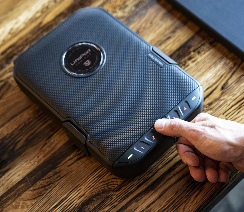 Person entering code on compact biometric safe with textured black exterior on wooden table