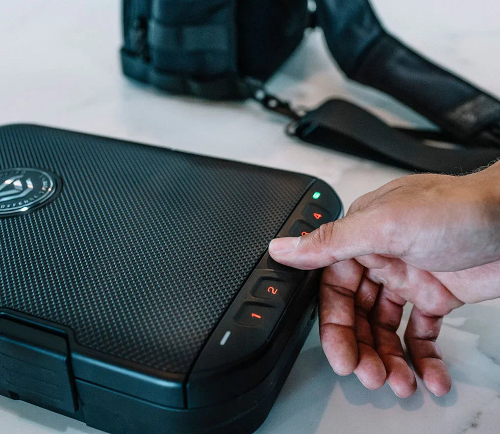 Hand entering code on keypad of compact portable biometric safe on countertop