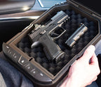 Portable biometric safe with foam interior holding a handgun and small accessory in a car.