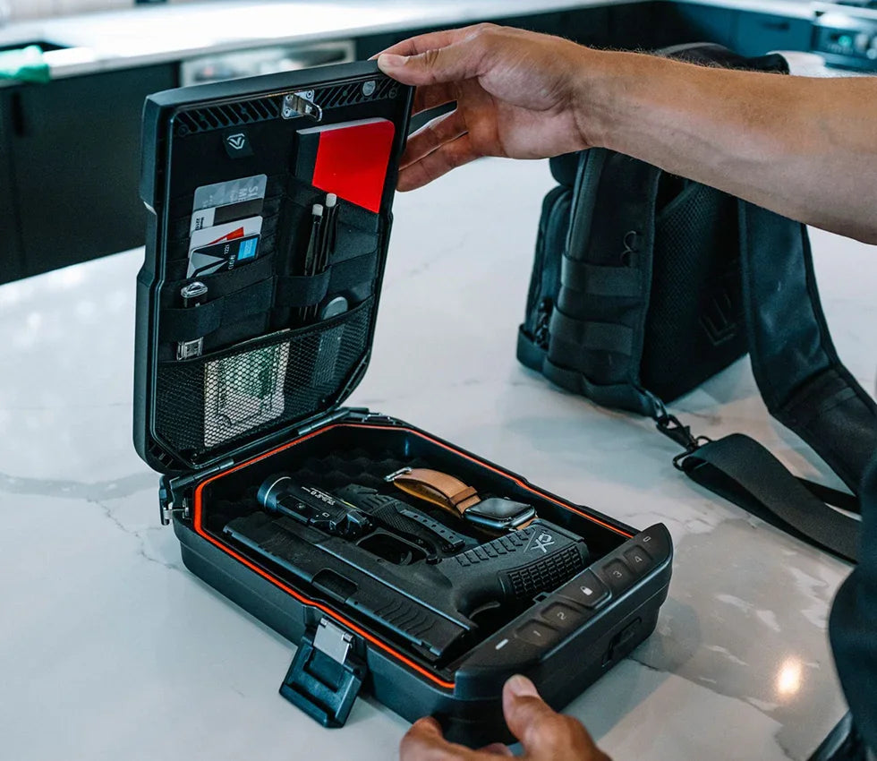 Hand opening a biometric portable safe with organized compartments and a handgun inside