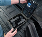 Portable lockbox safe open in a car trunk holding two handguns, magazines, and ID cards.