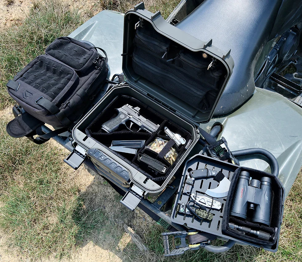 Open portable safe on ATV with handgun, magazines, binoculars, and tactical gear outdoors