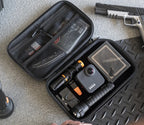 Open portable safe with camera, flashlight, multitool, and gear organizer on carpet