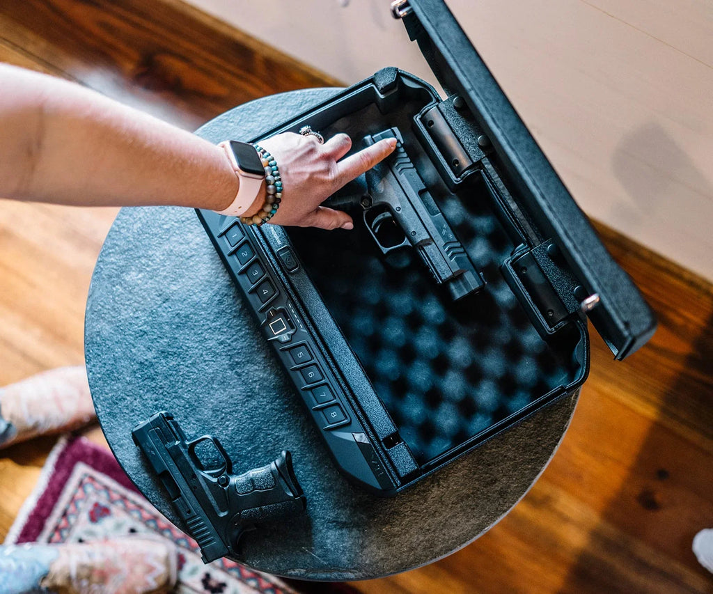 Person placing a handgun in a biometric foam-padded safe on a table.