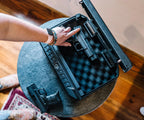 Person placing a handgun in a biometric foam-padded safe on a table.