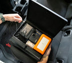 Portable safe in car holding valuables like wallet, passport, camera, cash, and hard drive