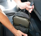 Portable olive green travel safe secured with a cable lock inside a backpack